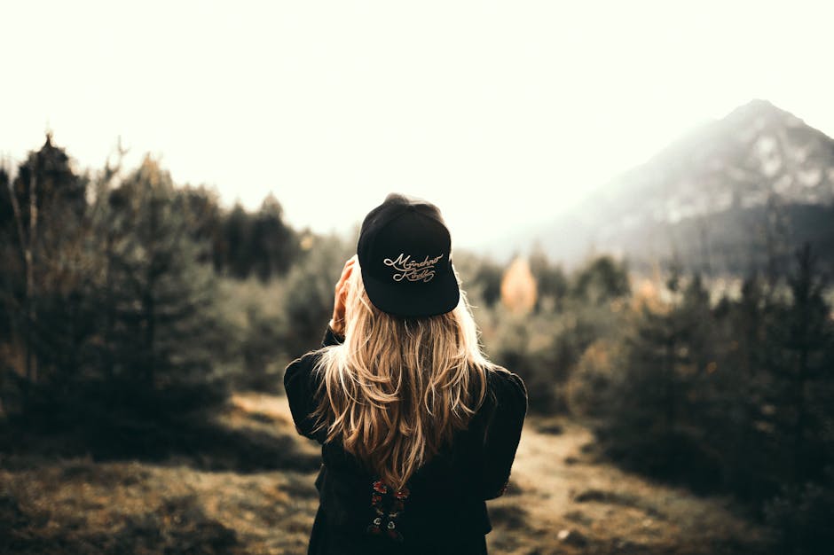 A woman in black cap and sweater enjoys a mountain view, embracing outdoor adventure